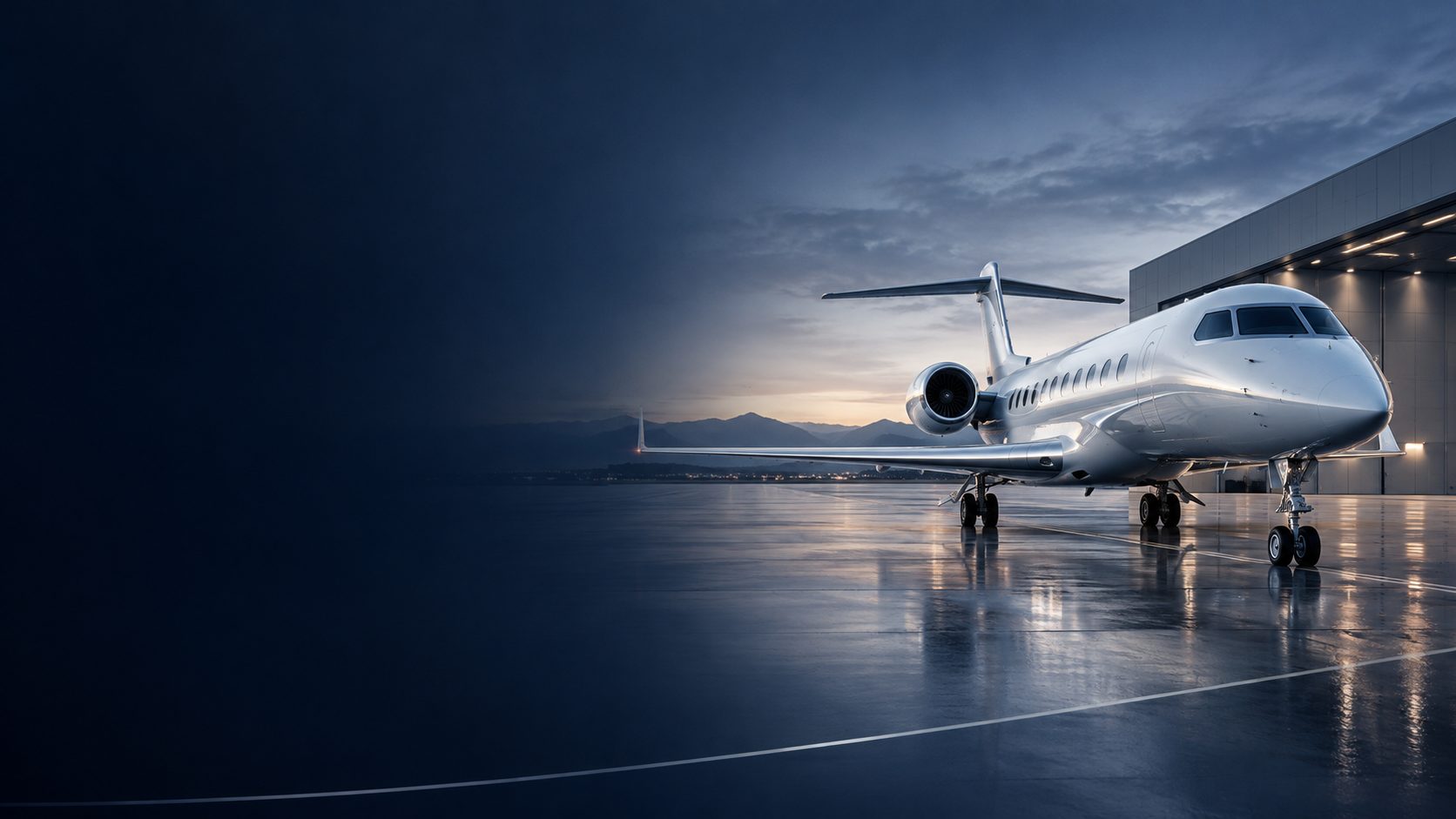 Business jet parked outside a lit hangar at dusk